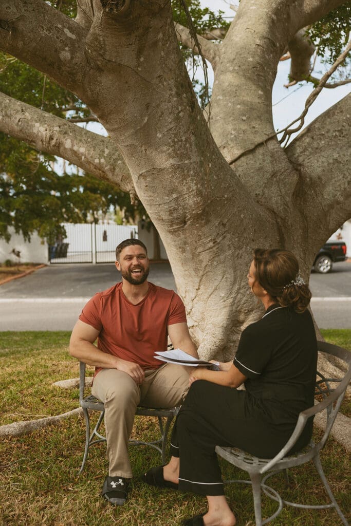 bride and groom sitting down and exchanging private vows outdoors