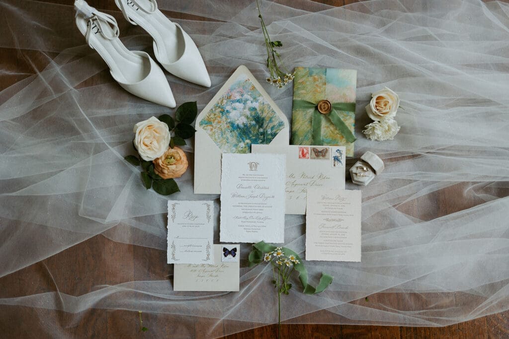 elegant wedding detail photos flatlay of wedding invite suites, loose florals and bridal shoes