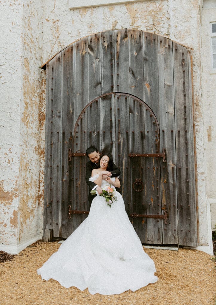 bride and groom in front of a rustic wooden door