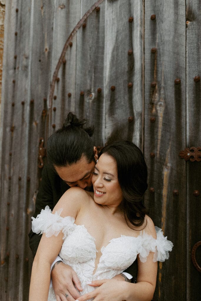 bride and groom in front of a rustic wooden door