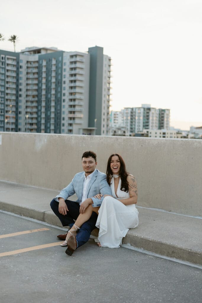 couple sitting on the ground with city skyline in the background on a garage rooftop in st pete florida