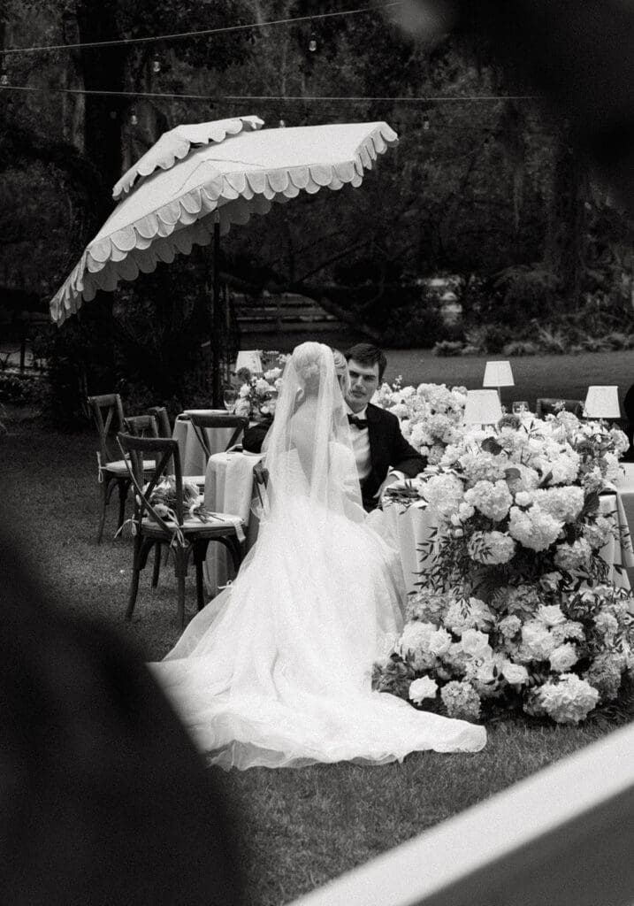bride and groom sitting at the decorated wedding reception table