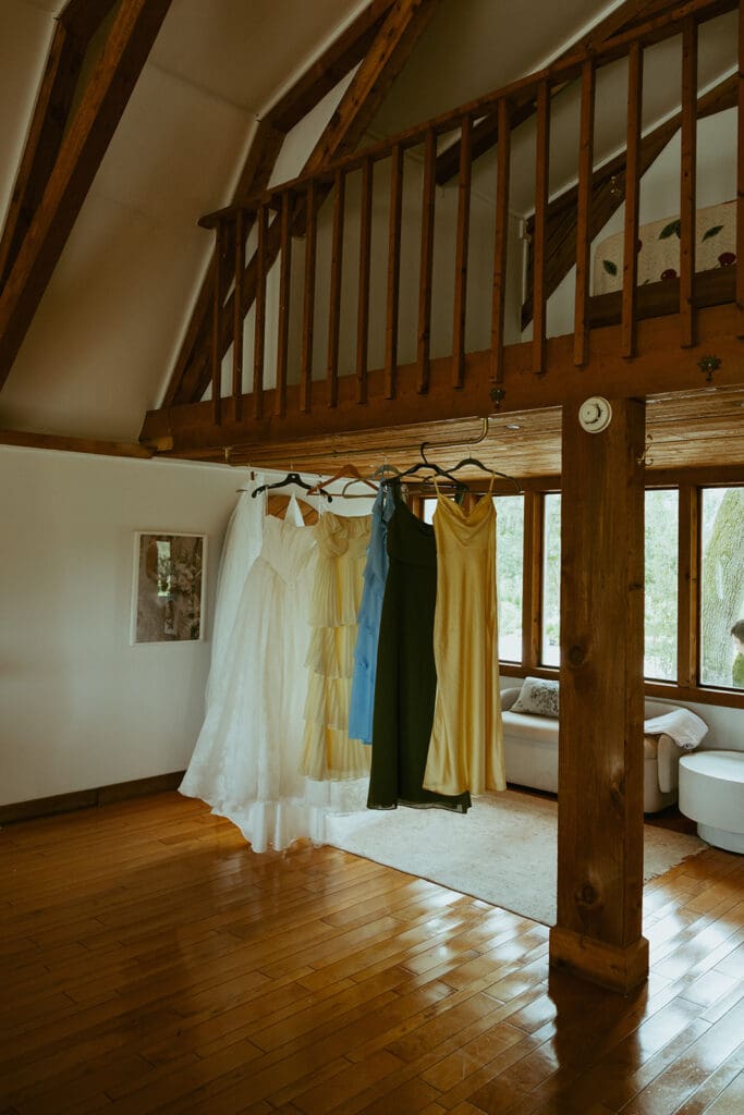 bride and bridesmaid dresses hanging from a balcony