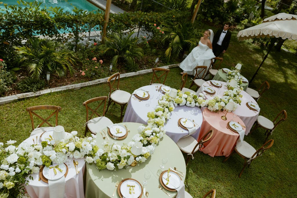 bride and groom walking to their uliana estate outdoor reception space, tables decorated with pastel linens and white floral runners